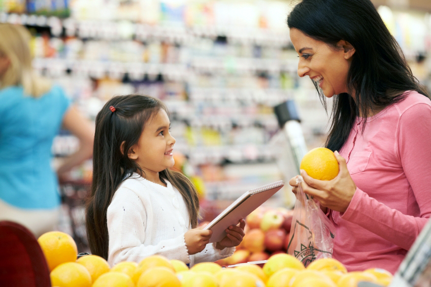 Mother And Daughter At Fruit Counter In Supermarket With List