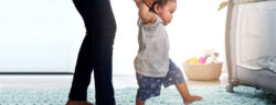 Mother holding hands of a baby taking first steps.