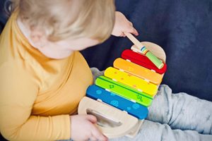 Child sitting in a chair playing musical instrument.