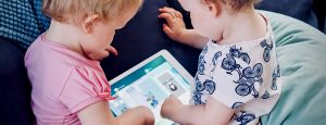 Two babies interact with a shared tablet.