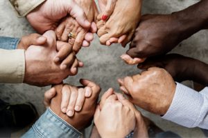 Overhead view of diverse group of hands holding on to one another in support.